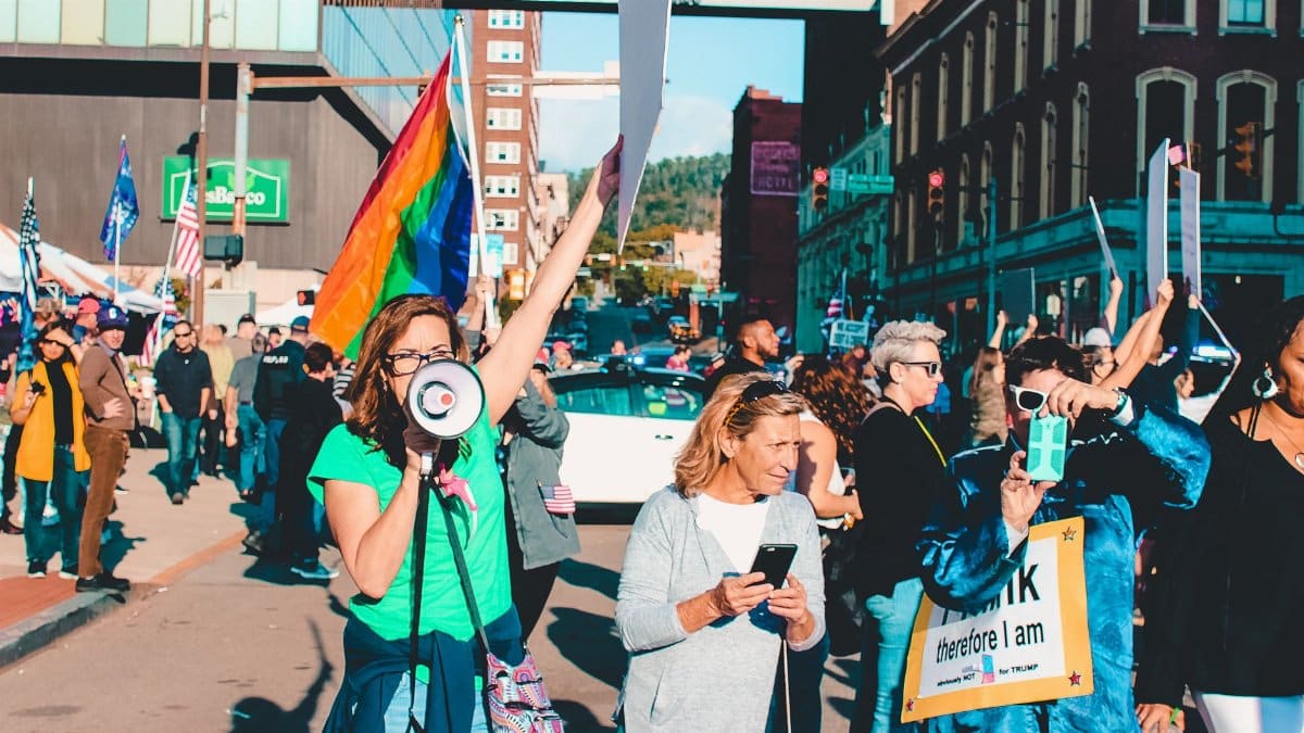A vibrant protest with diverse participants holding flags and signs on a city street.