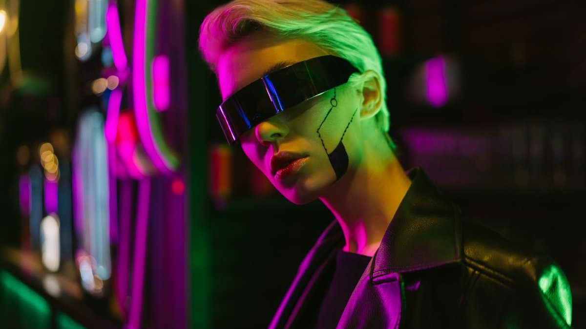 Stylish woman in cyberpunk glasses with neon lights and futuristic makeup.