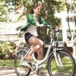 Female cyclist enjoying a sunny ride on her electric bike in the park.