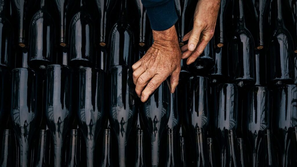 Close-up of hands organizing wine bottles in Nouvelle-Aquitaine's artisanal scene.