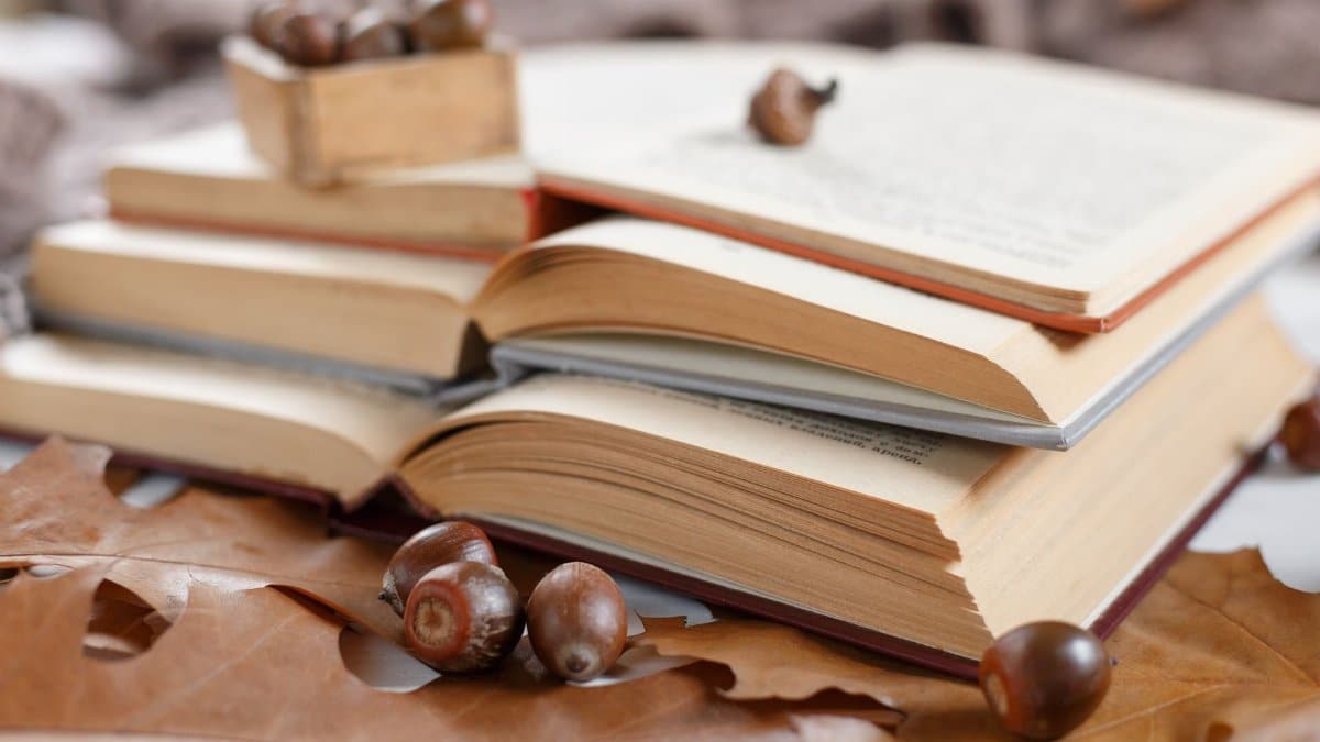 A cozy autumn scene with open books, acorns, and leaves creating a warm literary atmosphere.