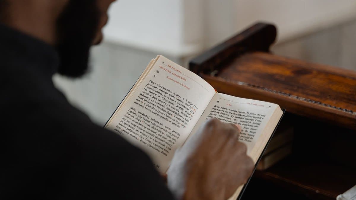 A man reading a religious book inside a church, focusing on a spiritual moment.