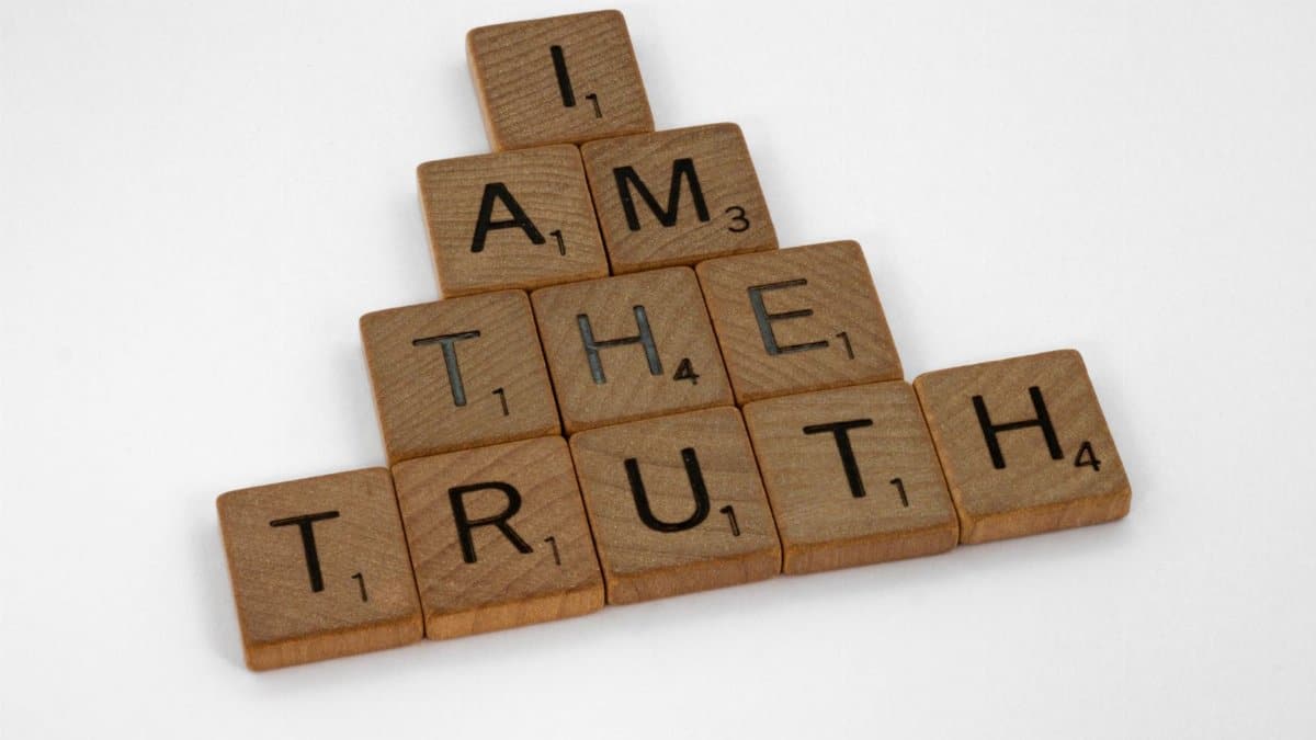 Scrabble tiles arranged on a white surface to spell 'I Am The Truth' in a pyramid shape.