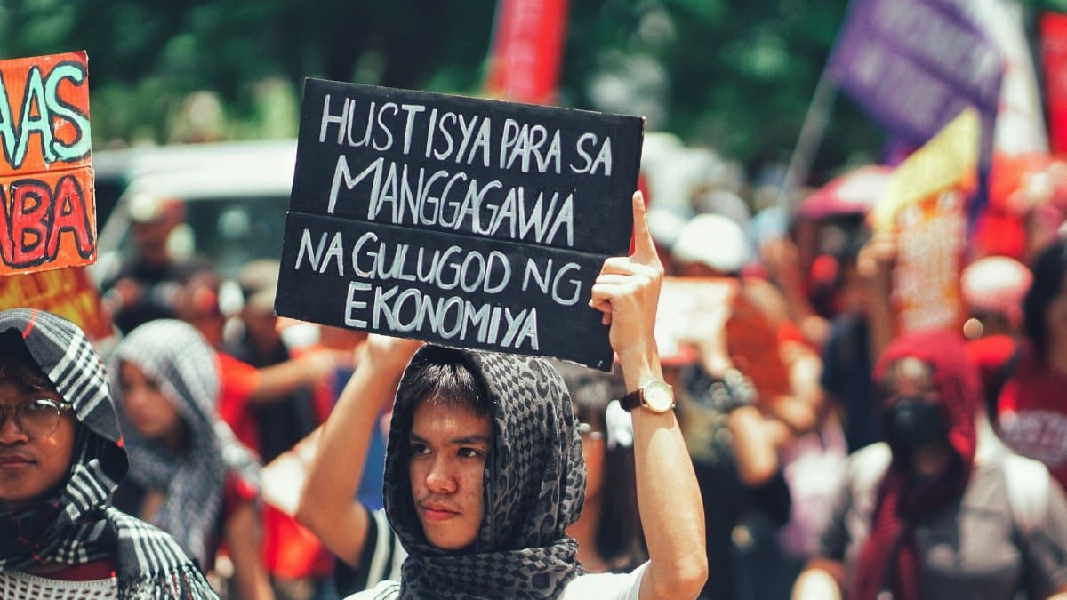 Protesters gathered outdoors holding signs demanding economic justice and workers' rights.