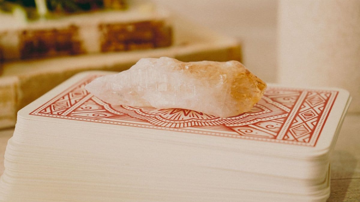 A quartz crystal resting on tarot cards, ideal for fortune telling and spiritual activities.