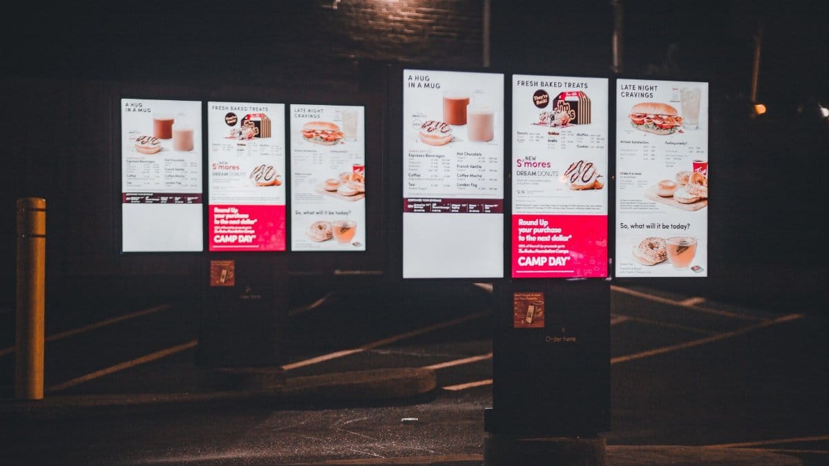 Nighttime view of an illuminated fast food drive-thru menu with digital display and clear copyspace.
