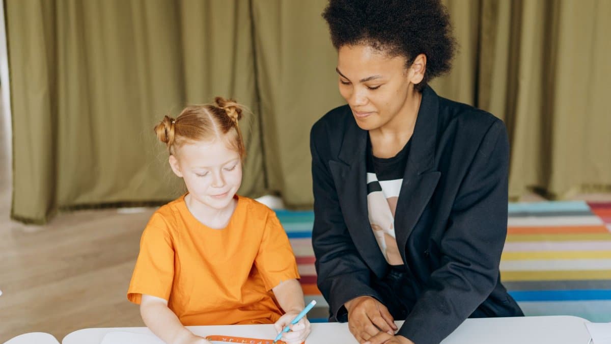 Child in colorful classroom learning with attentive teacher, fostering education and growth.