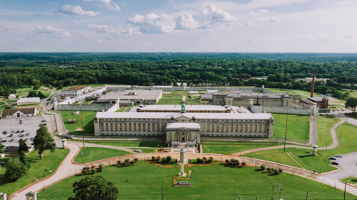 Aerial view of Atlanta Federal Penitentiary surrounded by greenery under a clear sky.