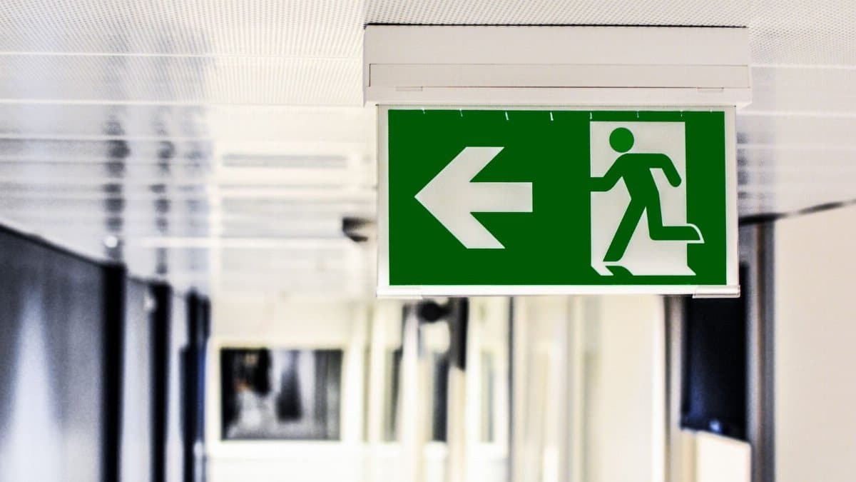 Green emergency exit sign with directional arrow in a hallway.
