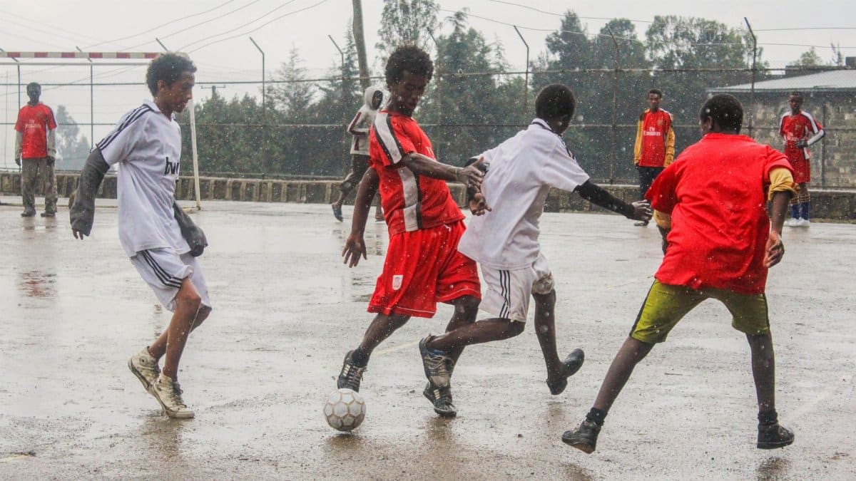 Youth playing a competitive soccer game in the rain, showcasing teamwork and energy.
