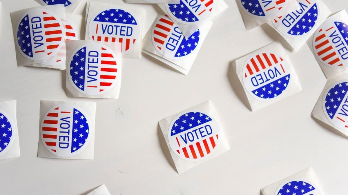 Top view set of small round stickers with flag of United Stated and I voted text scattered on white surface