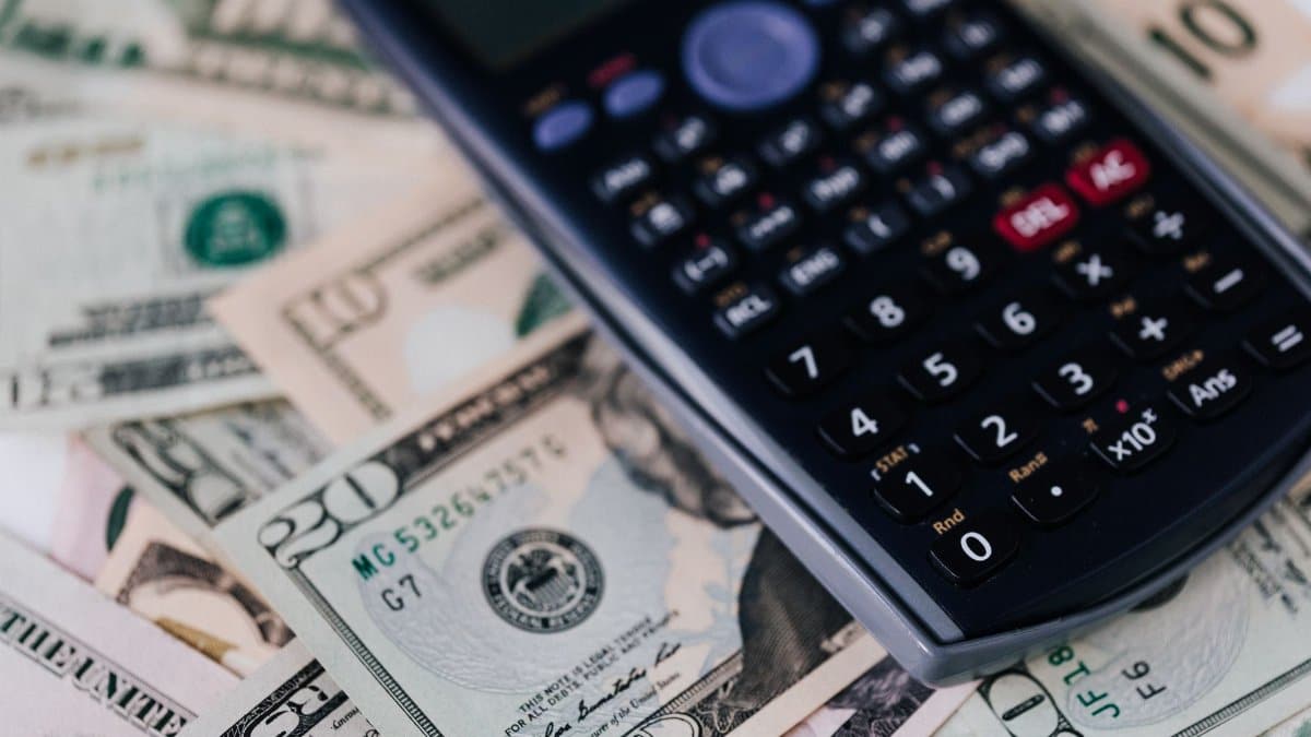 From above of electronic calculator placed over American cash paper money for budget planning and income and expenses calculation