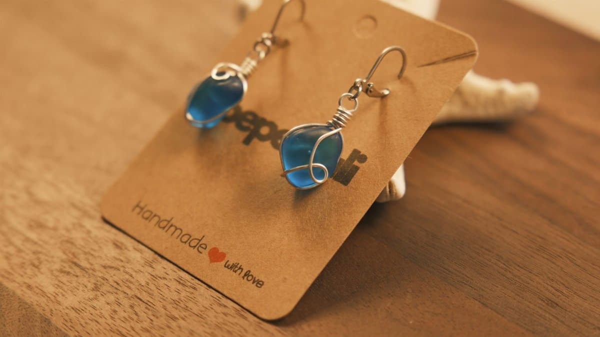 Chic handmade earrings featuring blue stones wrapped in wire on a brown background.