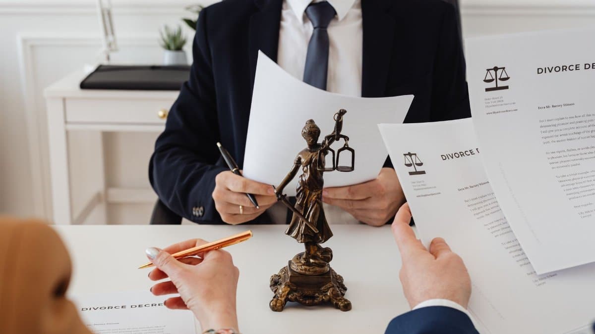 Legal professionals reviewing divorce documents in a law office with a Lady Justice statue.