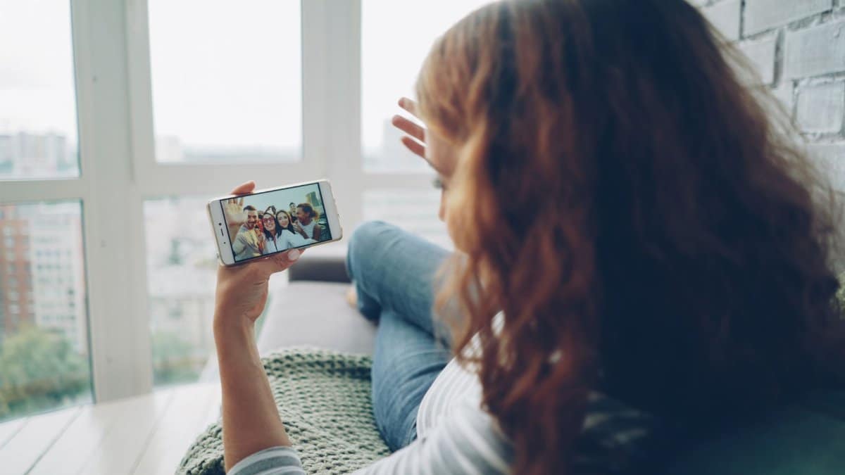 Woman relaxing indoors while video chatting with friends on smartphone.