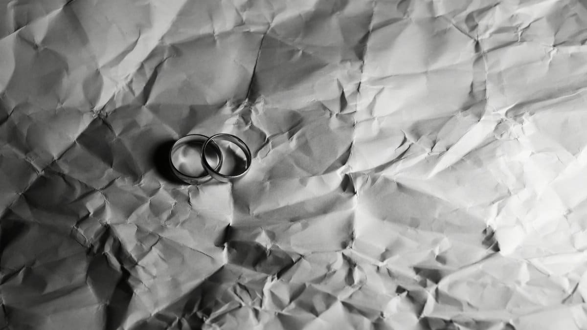 Two elegant wedding rings on crumpled paper background in monochrome tone.