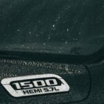 A close-up of a black Dodge Ram 1500 Hemi with rain droplets on the surface, showcasing automotive design.