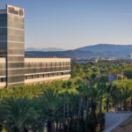 View of Hilton hotel surrounded by palm trees with mountains in the background at sunrise.