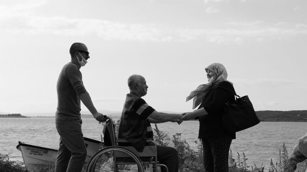 A touching moment with an elderly couple holding hands by a serene lake, showcasing love and companionship.
