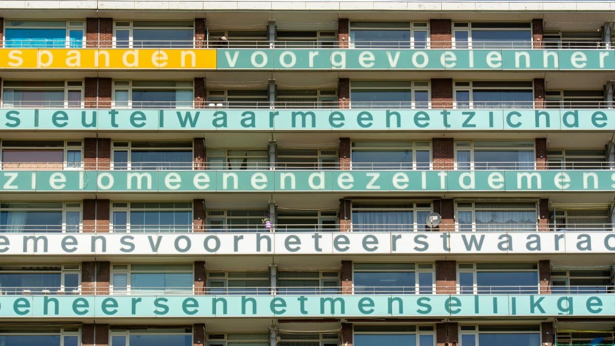 A vibrant facade of a residential block in Delft, showcasing colorful text in a modern urban setting.