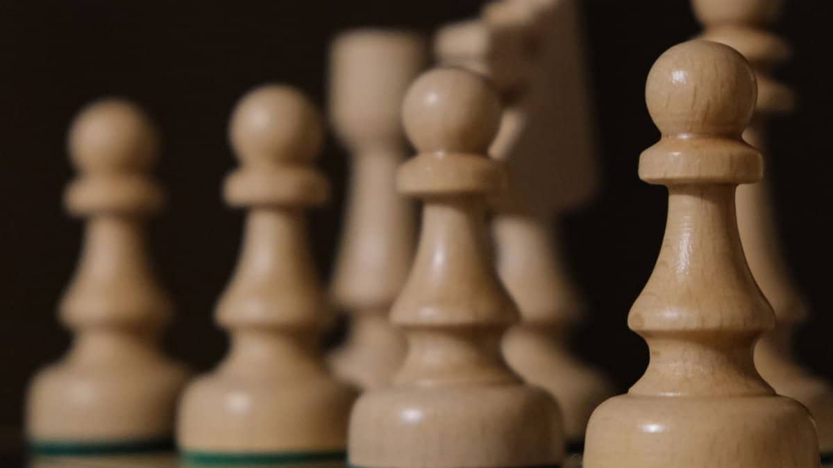 Close-up of chess pieces on board, highlighting pawns in strategic arrangement.