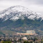 A winter aerial view of snow-capped mountains with San Bernardino cityscape in the foreground, California.