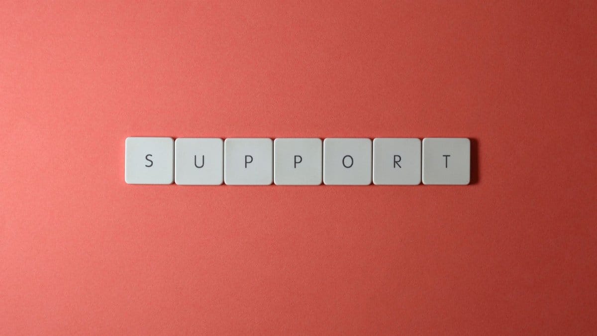 Close-up of the word 'support' spelled with keyboard keys on a red background.