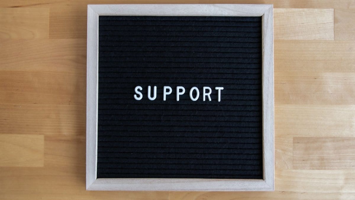Black letter board displaying the word SUPPORT on a wooden table, offering ample copyspace.