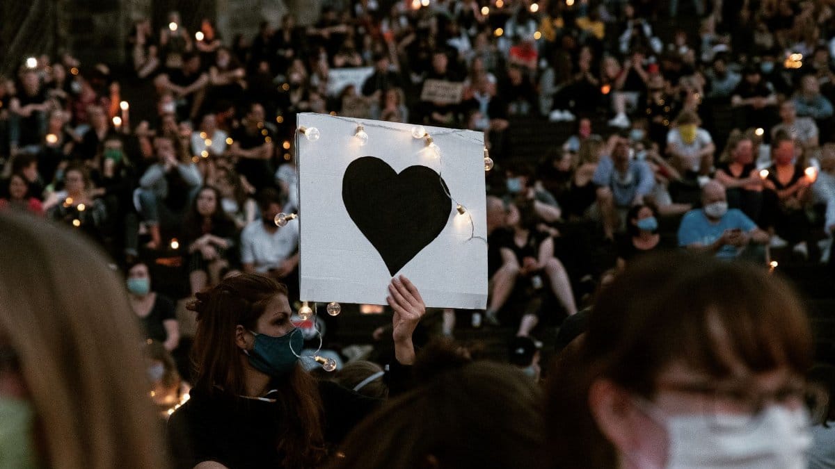 People gather at a candlelit vigil in Erfurt holding signs for love and peace.