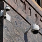 Surveillance cameras mounted on the ornate corner of a city building, ensuring security.