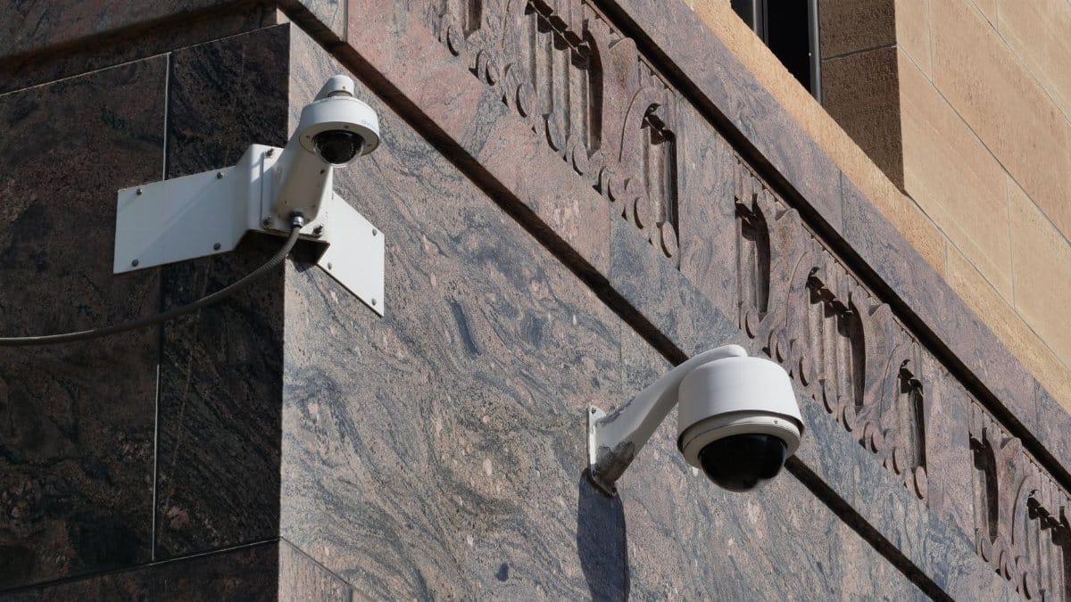 Surveillance cameras mounted on the ornate corner of a city building, ensuring security.