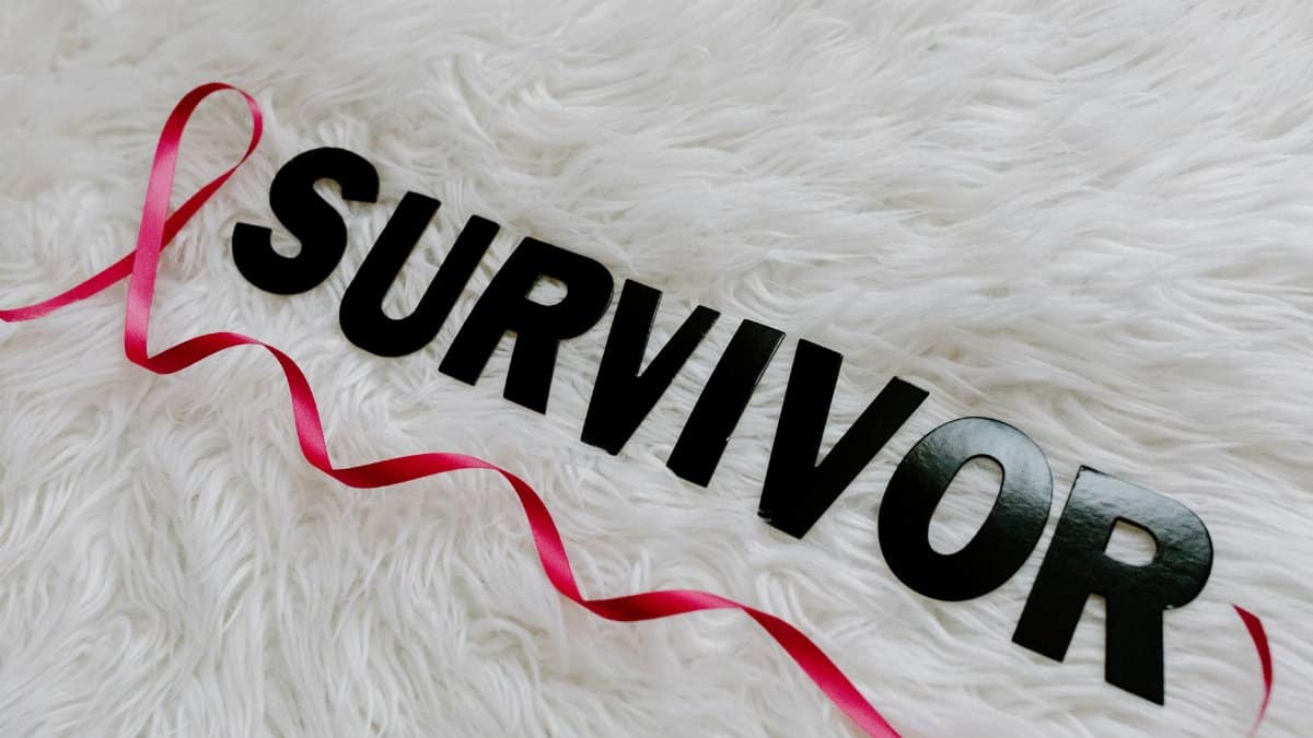 Pink ribbon with 'SURVIVOR' text symbolizing cancer awareness on white texture.