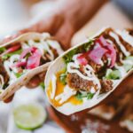 Delicious fresh tacos with fillings including lettuce, cheese, and pickled onions, ready to eat.