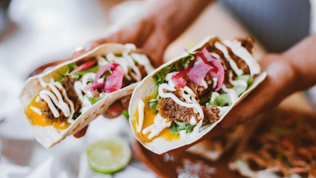 Delicious fresh tacos with fillings including lettuce, cheese, and pickled onions, ready to eat.
