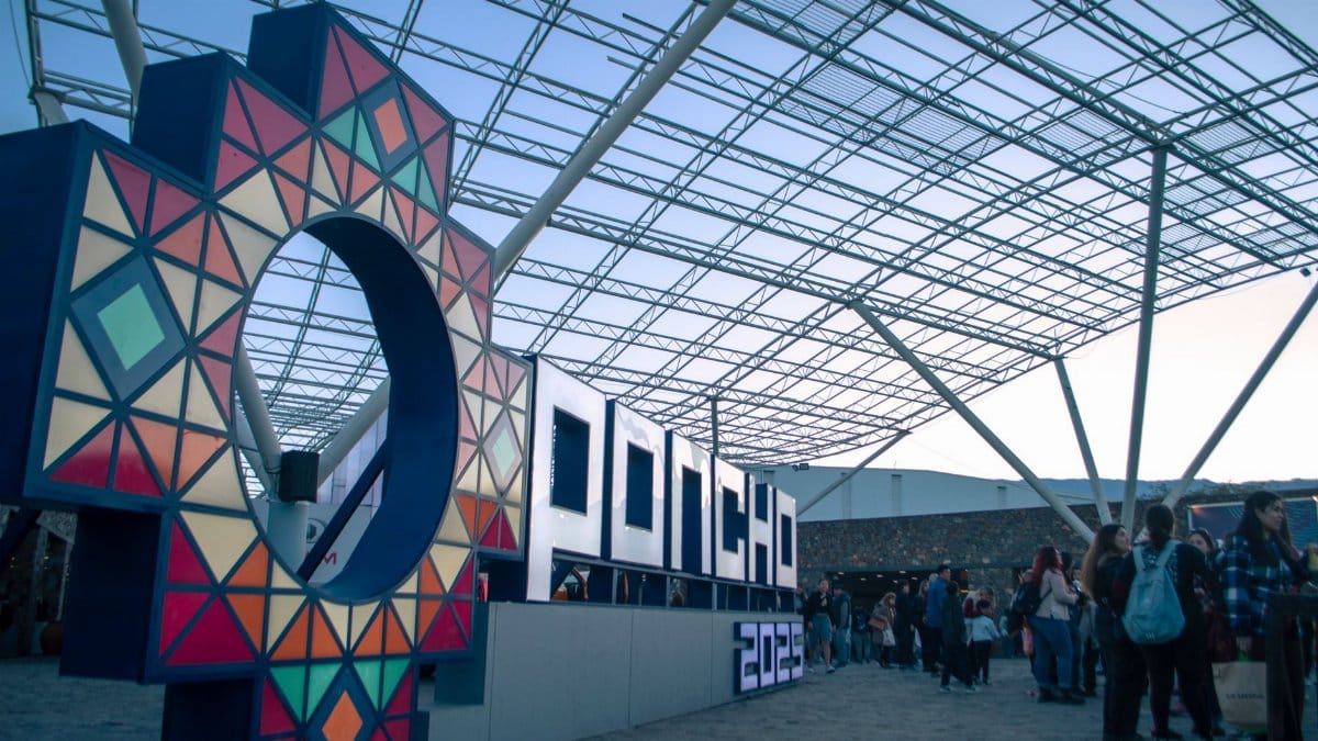Vibrant signage at a bustling indoor expo event with attendees gathering and colorful lighting.