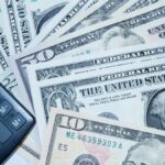 US dollars, calculator, and car keys representing finance and investment tools.