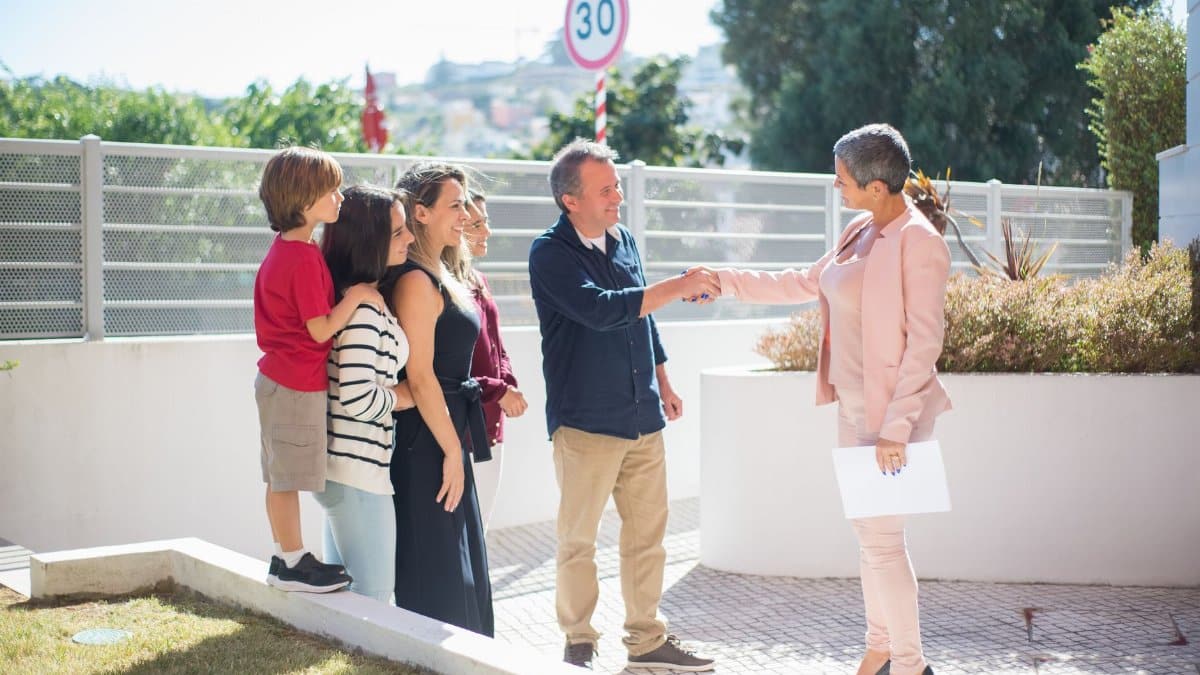 Family meets real estate agent outside home in Portugal, negotiating property deal.