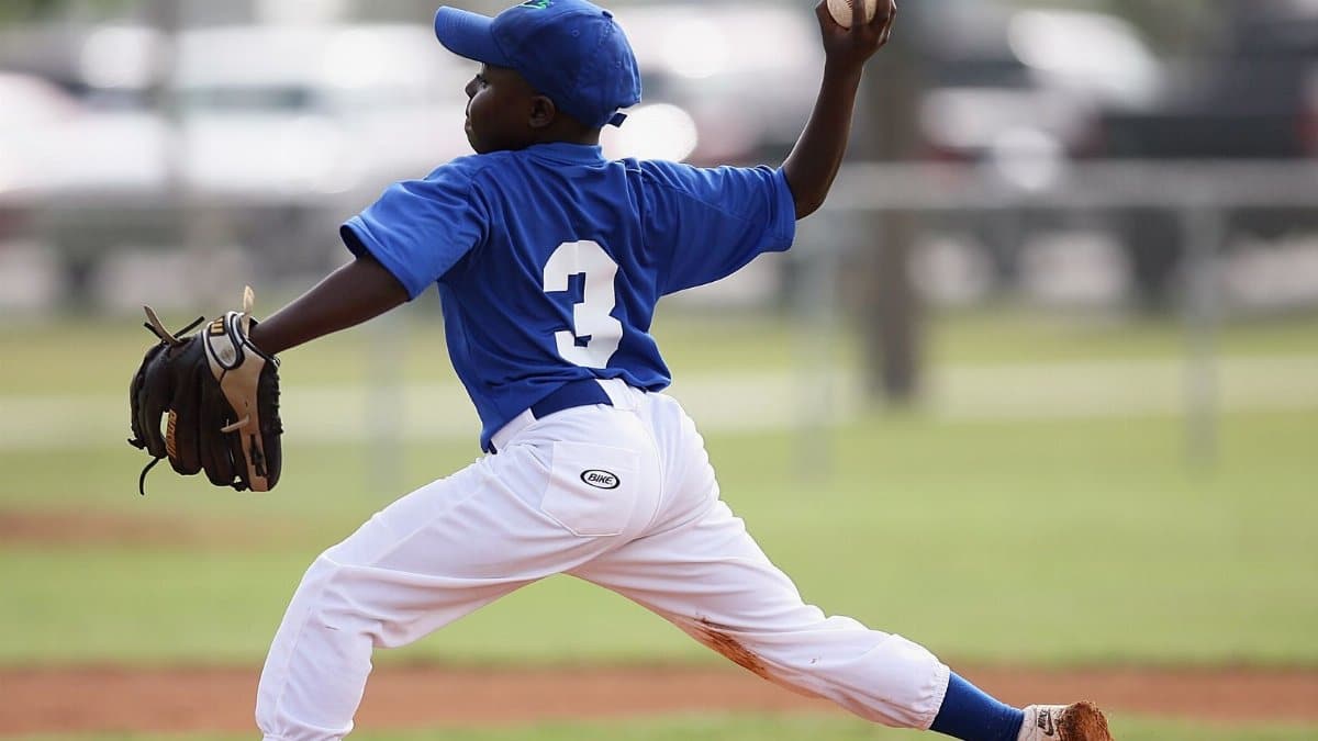 Young player pitching in a youth baseball game on a sunny day.