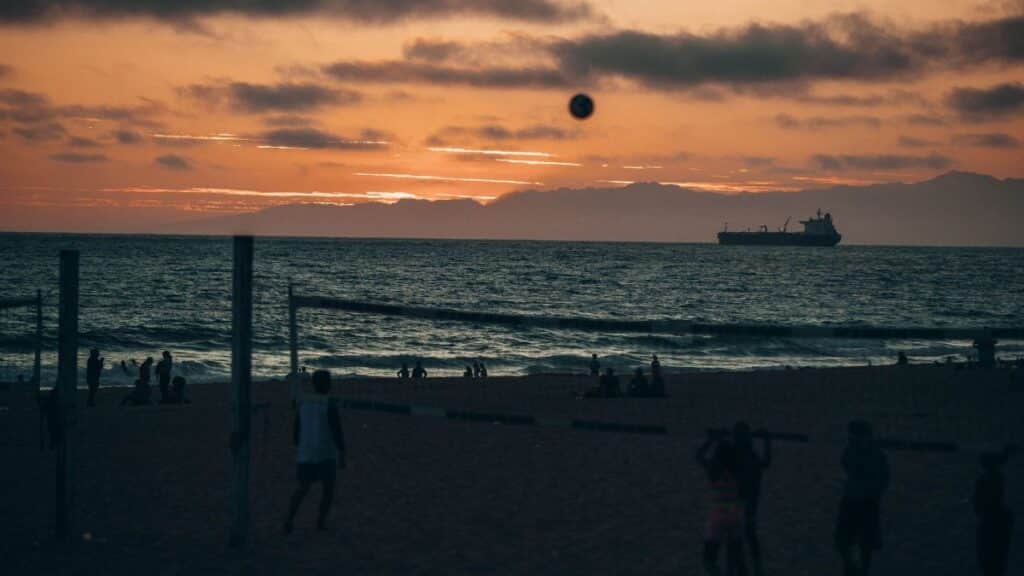 Silhouettes playing beach volleyball at sunset on Manhattan Beach, California.