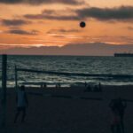 Silhouettes playing beach volleyball at sunset on Manhattan Beach, California.