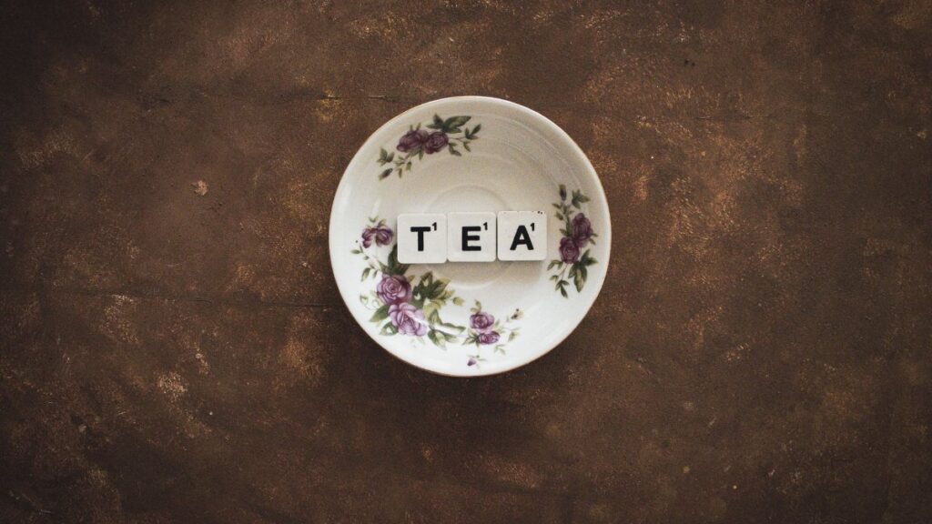 Artistic composition of TEA tiles in a floral saucer on a rustic backdrop.