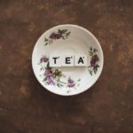 Artistic composition of TEA tiles in a floral saucer on a rustic backdrop.