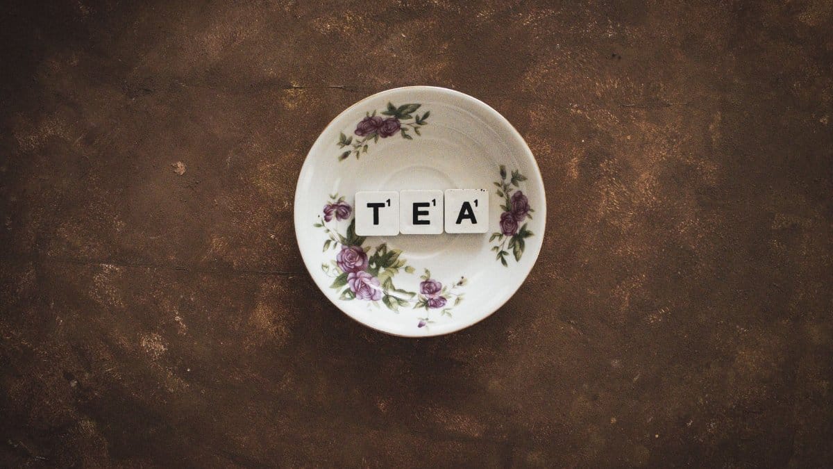 Artistic composition of TEA tiles in a floral saucer on a rustic backdrop.