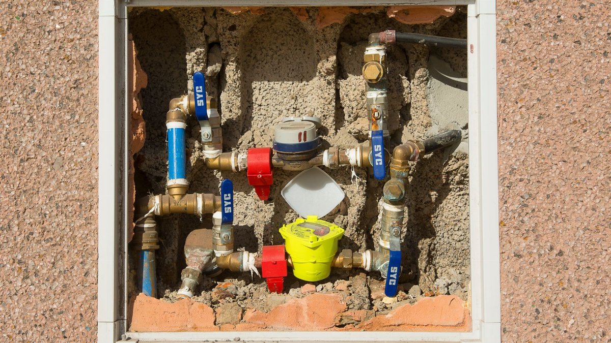 Detailed view of a complex water meter setup embedded in a concrete wall.