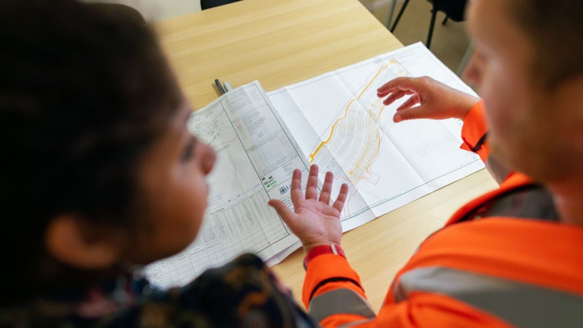 Two engineers reviewing construction blueprints on a table in an office setting.