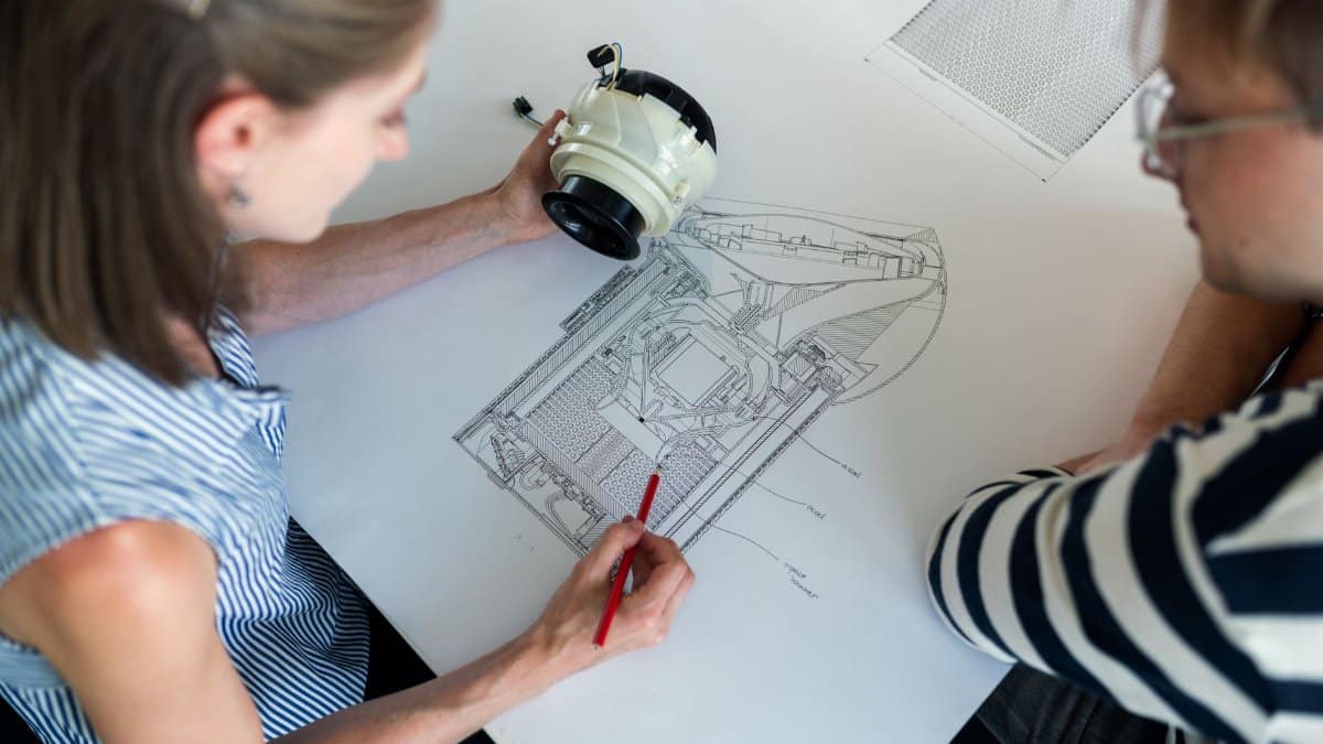 Two engineers collaborate over a detailed technical design blueprint, focusing on innovation and planning.