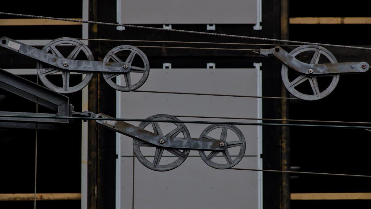 Detailed view of metallic pulleys on a modern building facade, capturing industrial design elements.