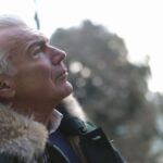 Profile of a senior man in a winter coat enjoying a peaceful outdoor moment.