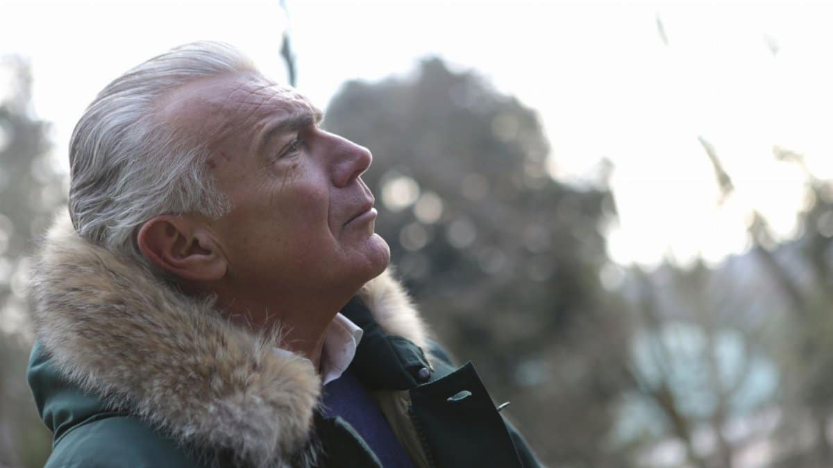 Profile of a senior man in a winter coat enjoying a peaceful outdoor moment.