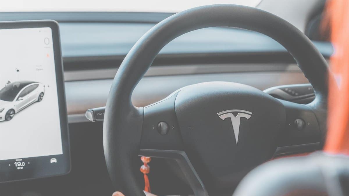 Close-up view of a Tesla electric car steering wheel and digital display, showcasing modern automotive design.